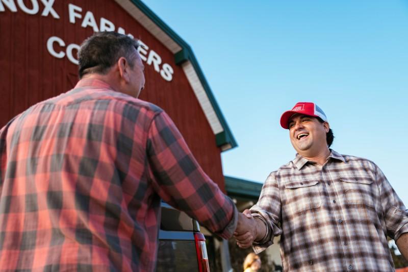 Farm Bureau agent shaking hands with farmer outside of Co-Op