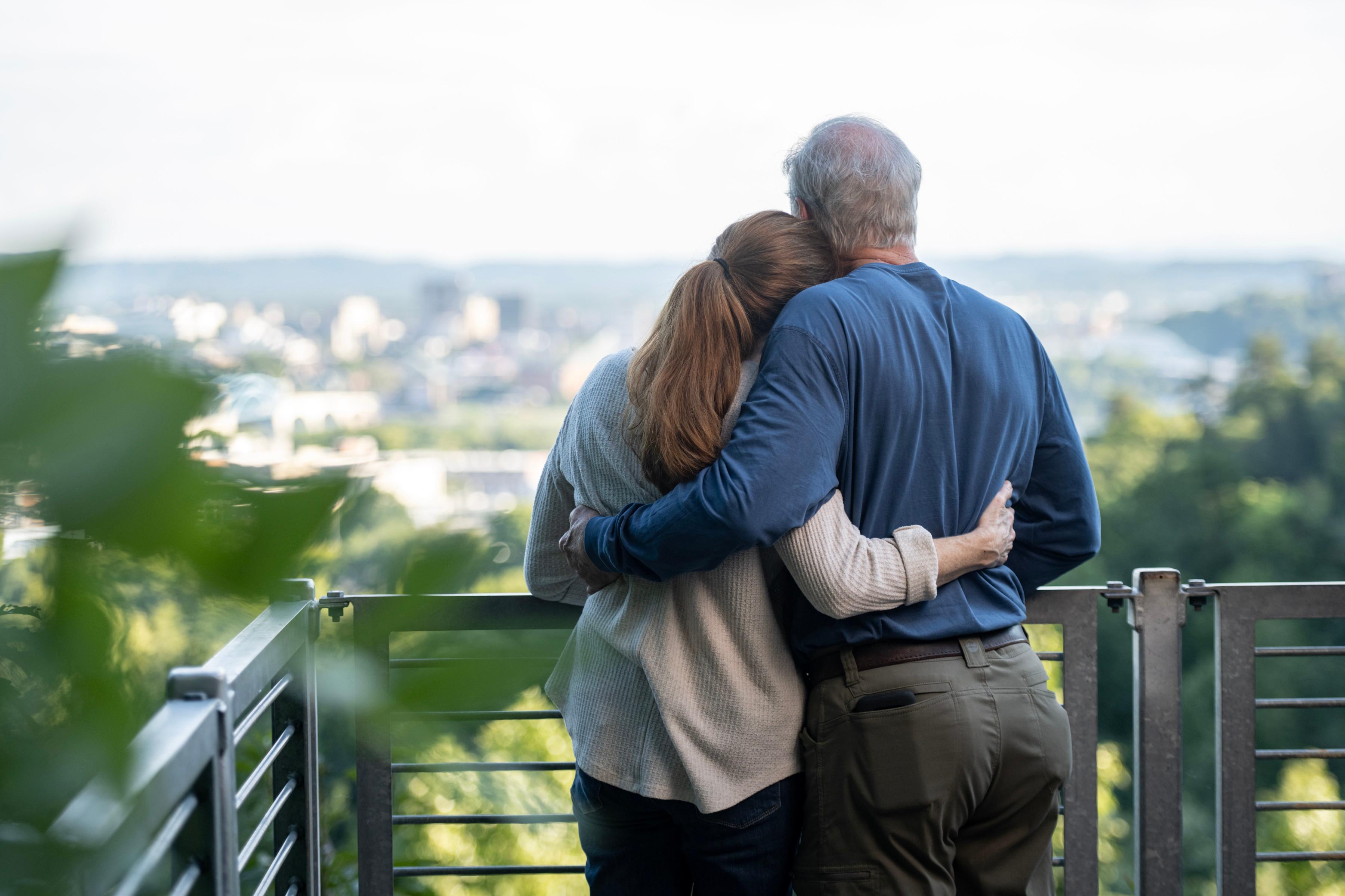 Older couple standing on balcony overlooking city