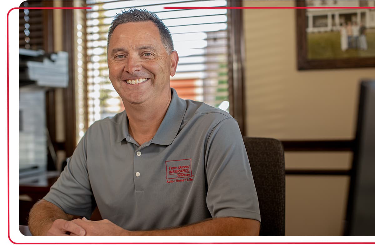 Farm Bureau Insurance of Tennessee agent smiling while sitting at his desk in a Farm Bureau Insurance of Tennessee office