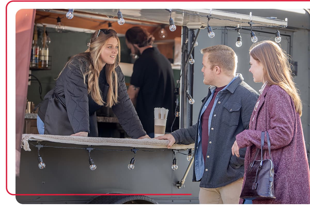 Couple getting food from a local food truck while talking to woman business owner