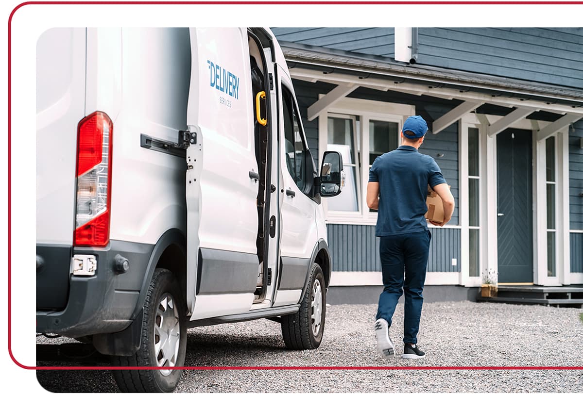 Delivery driver holding a package with a commercial delivery truck in the foreground.