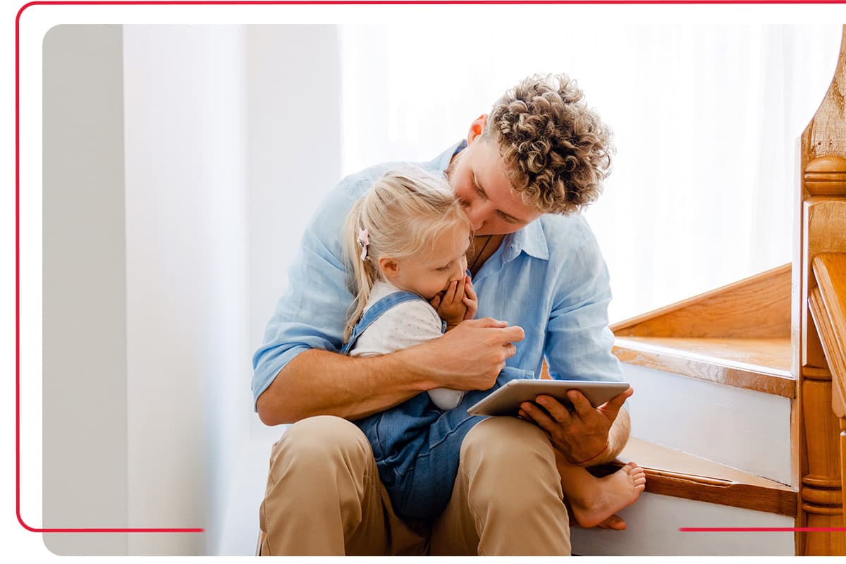 Father reading a book to his daughter on the staircase in their home