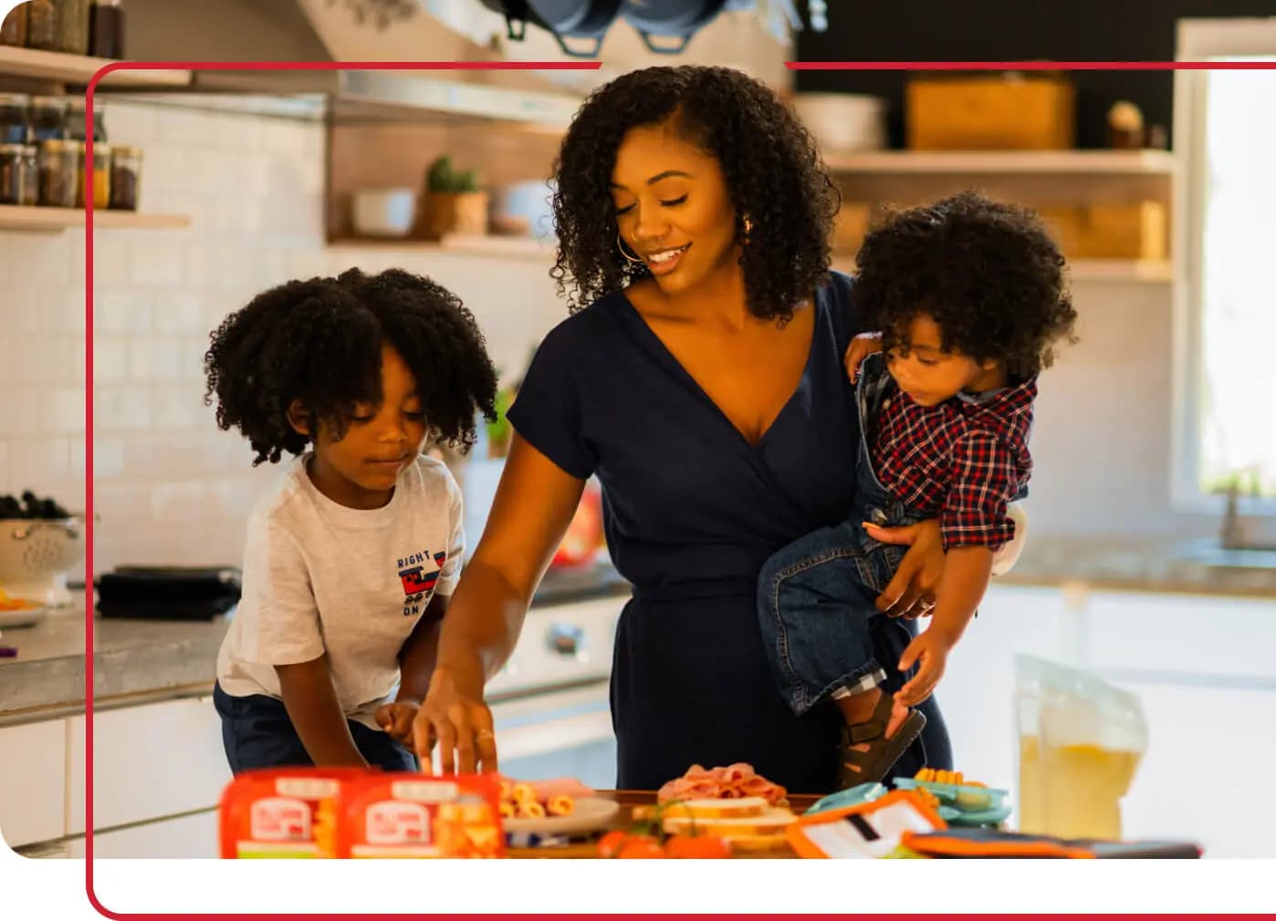 Mother with two young sons eating snacks off countertop in home kitchen