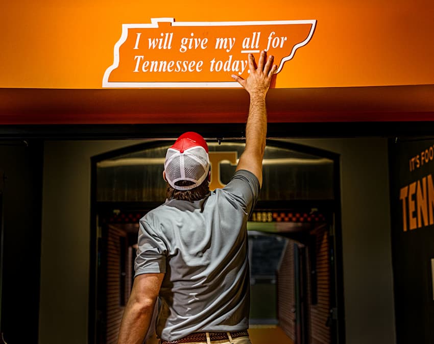 Farm Bureau Insurance of Tennessee agent slapping Tennessee Vols sign in the locker room of Neyland Stadium in Knoxville, Tennessee